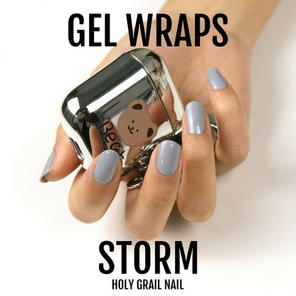 Storm grey gel wraps manicure on hand holding chrome nail polish bottle