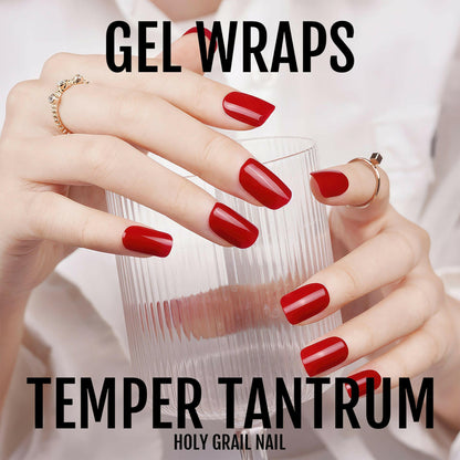 Hands holding glass showing red gel nail wraps with glossy crimson finish