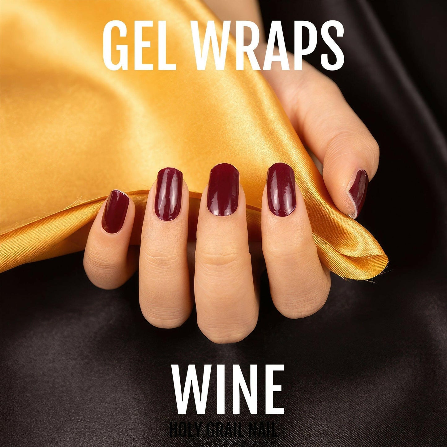 Deep wine red gel nail wraps on hand against golden fabric backdrop