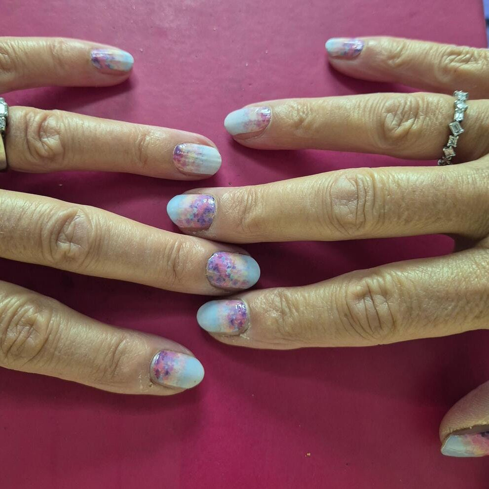 Hands wearing blue coral watercolour floral nail wraps with dreamy wildflower art design